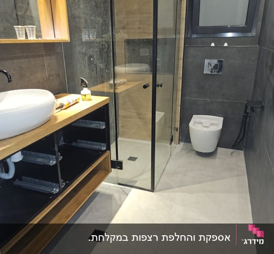 חדר אמבטיה עם ארון פתוח, כיור, מקלחון וכלי עבודה על השיש.